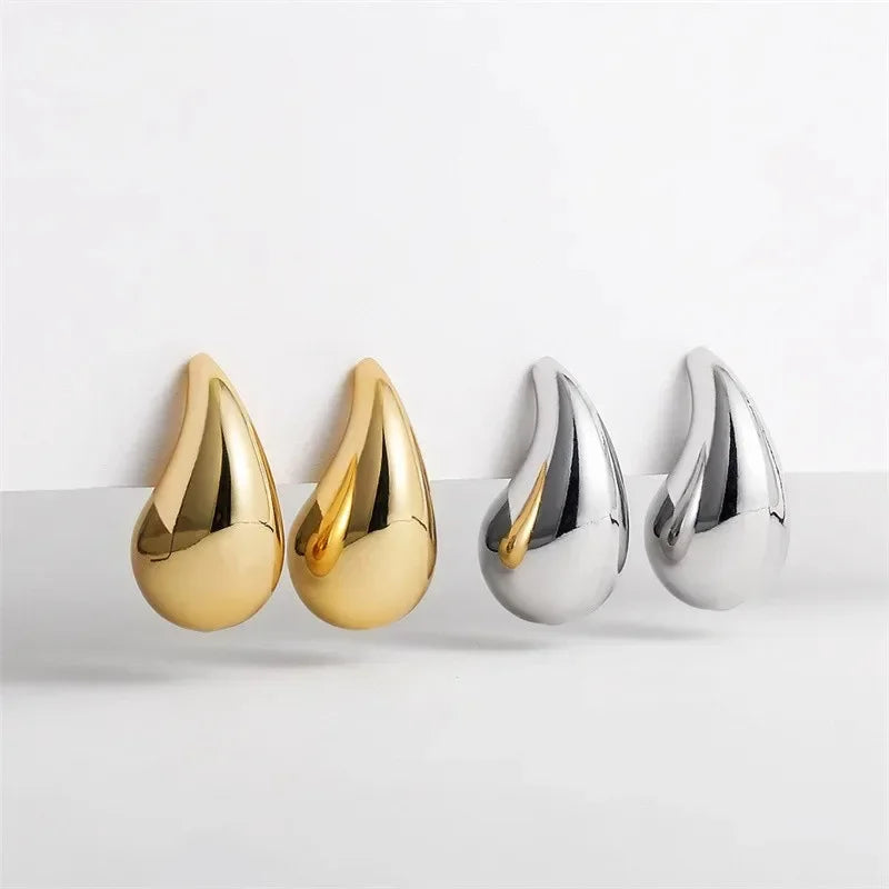 Two pairs of gold and silver teardrop-shaped earrings on a white background
