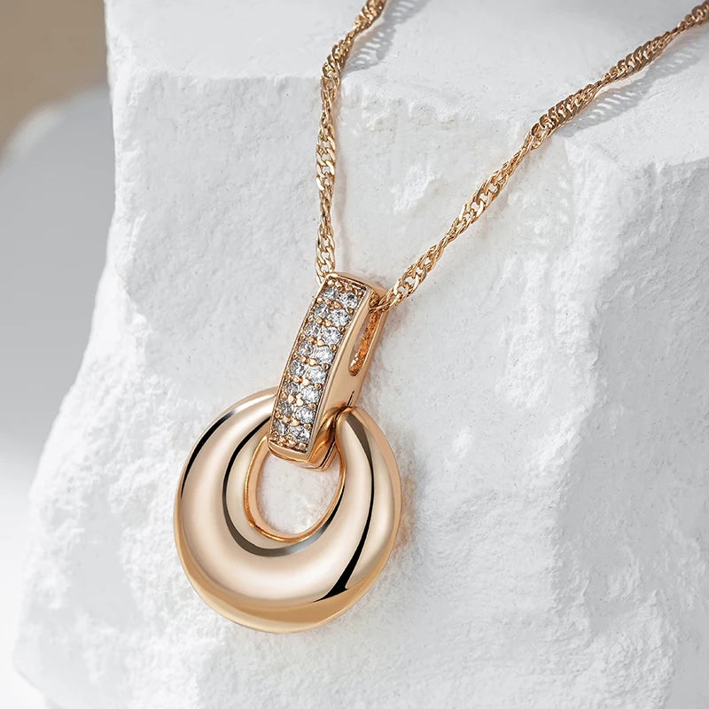 Elegant rose gold pendant necklace with crystal details showcased on a white stone background
