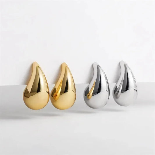 Two pairs of gold and silver teardrop-shaped earrings on a white background