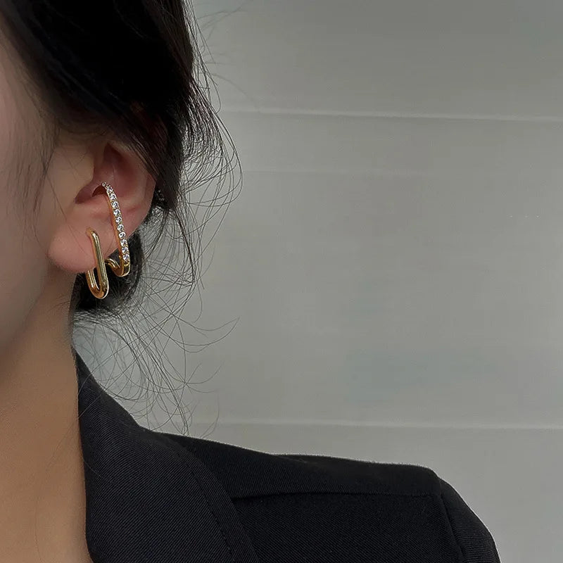 Close-up side view of a woman wearing glamorous gold link earrings with sparkling crystals, styled with a black blazer for a chic look.