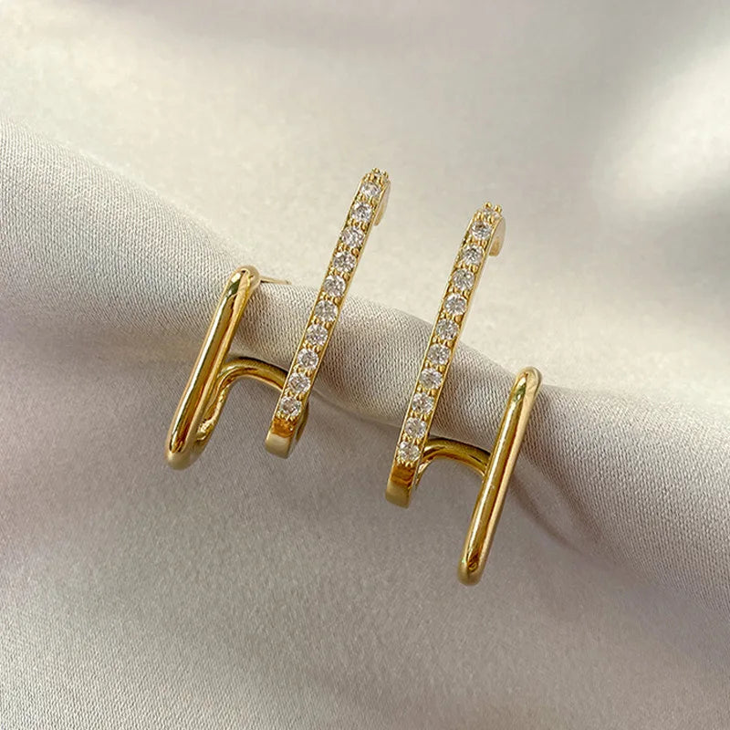 Pair of glamorous gold link earrings adorned with sparkling crystals, displayed on a soft ivory fabric background.