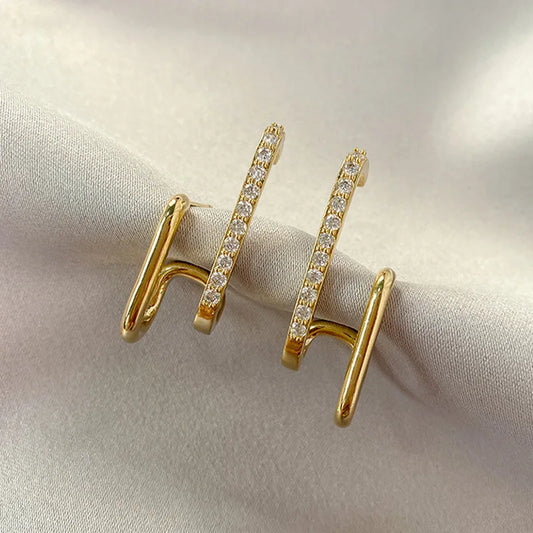 Pair of glamorous gold link earrings adorned with sparkling crystals, displayed on a soft ivory fabric background.
