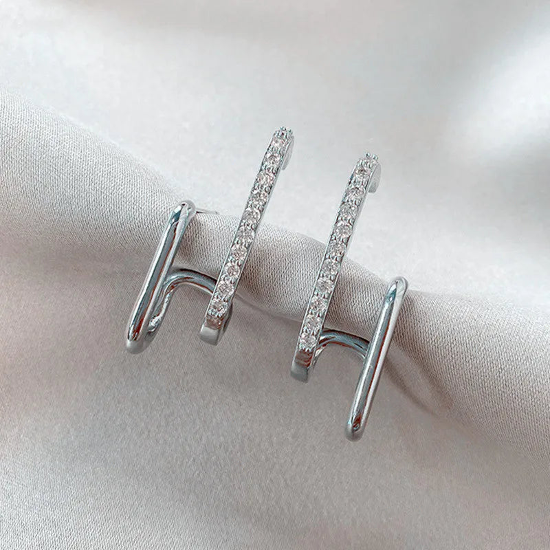 Pair of glamorous silver link earrings adorned with sparkling crystals, displayed on a soft white fabric background.