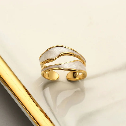 Retro gold open ring with white enamel wavy double-band design displayed on a white tray