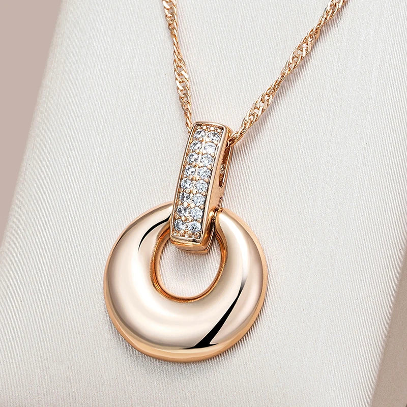 An elegant rose gold pendant necklace with a round, gold-tone pendant featuring a central diamond surrounded by smaller clear crystals, on a sleek adjustable chain.