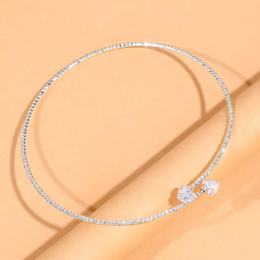 Sparkling solitaire choker necklace with cubic zirconia stones displayed on a soft beige surface.